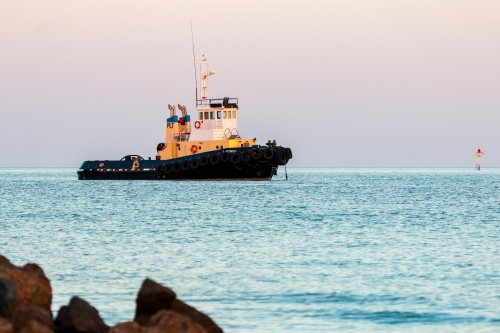 tug boat moored in bay in dawn light - Australian Stock Image