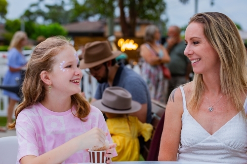 Tween girl eating snow cone and chatting with parent while out together - Australian Stock Image
