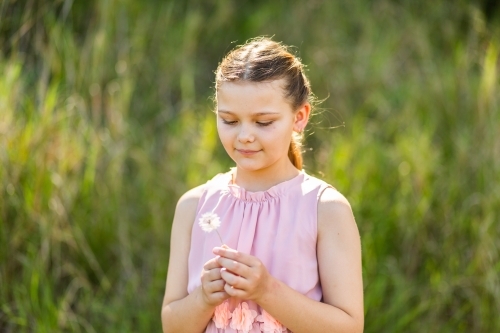 Tween girl holding a dandelion flower in nature outside