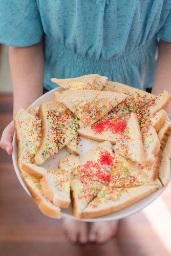 Tween girl holding fairy bread on a plate - Australian Stock Image