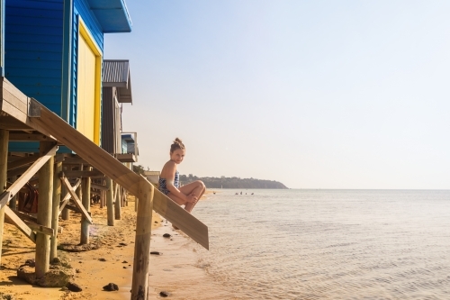Tween girl sitting on stairs at a beach box, Mt Martha - Australian Stock Image