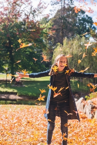 tween girl throwing autumn leaves - Australian Stock Image