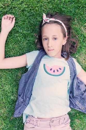 tween girl with watermelon t-shirt lying on the grass - Australian Stock Image