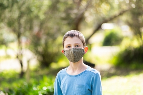 Tween kid outside in park with face mask on during covid pandemic - Australian Stock Image
