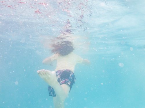 Tween kid swimming underwater in backyard pool water in summer - Australian Stock Image