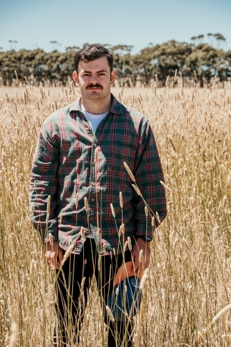 twenty something man standing in long grass in a rural area. - Australian Stock Image