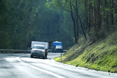 two 4WD'S towing caravans uphill on bush road - Australian Stock Image