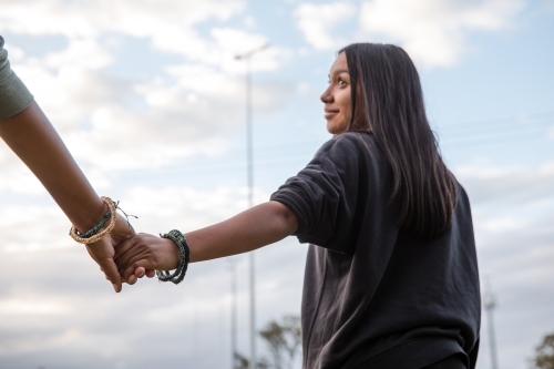Two Aboriginal girls wearing traditional woven bracelets, holding hands - Australian Stock Image