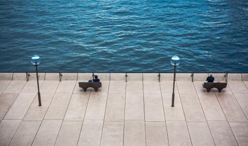 Two benches two people two streetlights with water background