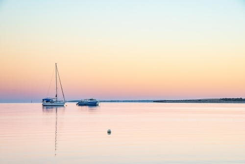 Two boat on a clear still morning water at dawn - Australian Stock Image