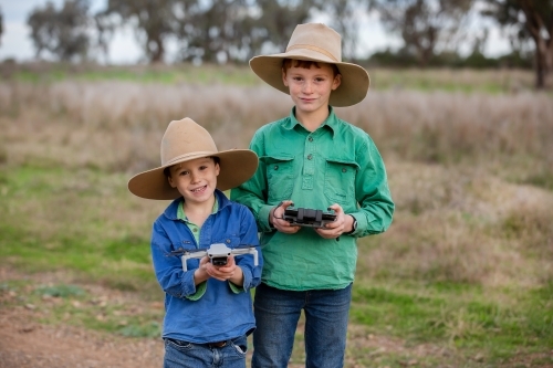 Two boys using a drone on a farm