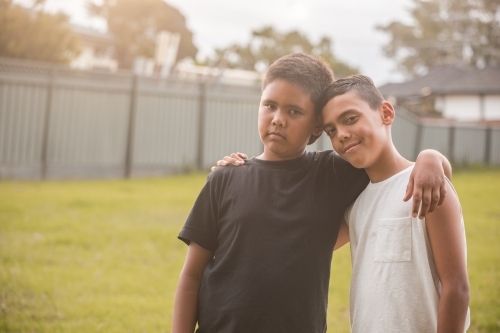 Two boys with their arms around each other outdoors - Australian Stock Image
