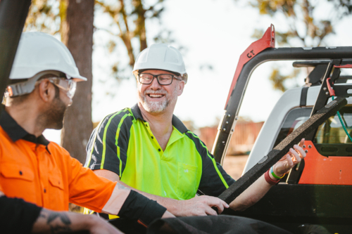 Two builders standing next to ute workmates smiling together - Australian Stock Image