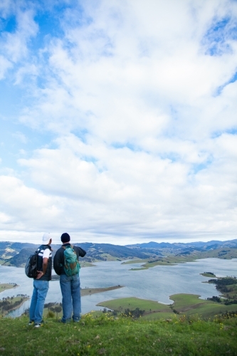 Two bushwalkers standing on a hill overlooking Lake St Clair - Australian Stock Image