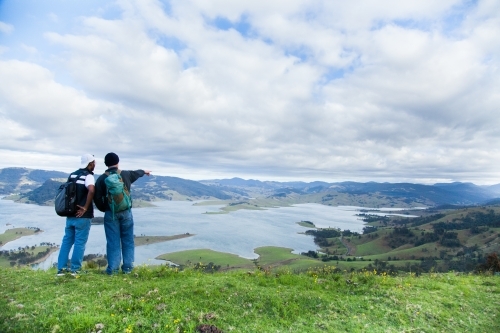 Two bushwalkers standing on a hill overlooking Lake St Clair - Australian Stock Image