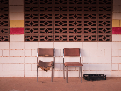 Two chairs in front of the tiled wall of a deserted building in outback Australia - Australian Stock Image