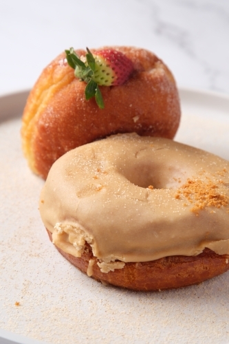 two donuts on a plate with fresh strawberry and sugar glaze - Australian Stock Image