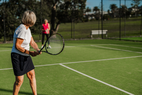 Two elderly women enjoying a game of tennis outdoors, showcasing active lifestyle and friendship. - Australian Stock Image