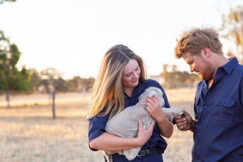 Two farm workers with a baby lamb