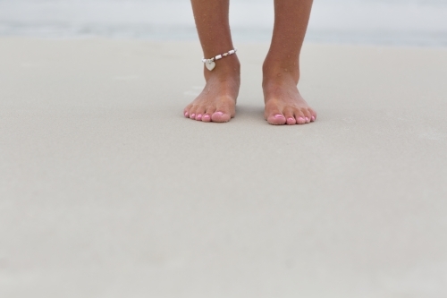 Two feet standing on sandy beach - Australian Stock Image