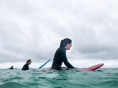 Two female surfers waiting for next wave on surfboards in ocean