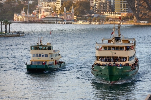 Two ferries crossing the water besides the Harbour Bridge
