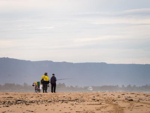 Two fishermen talking on the beach in the distance - Australian Stock Image