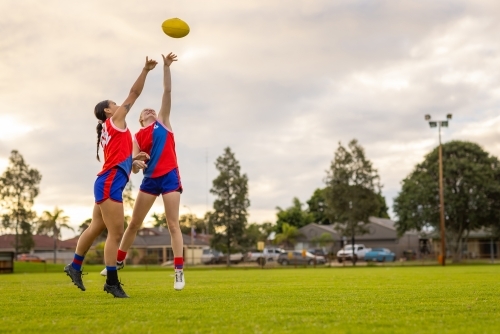two footy players stretching up to tap the ball away - Australian Stock Image