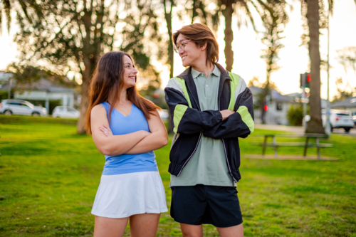 Two friends enjoying each other's company at a park during sunset. - Australian Stock Image