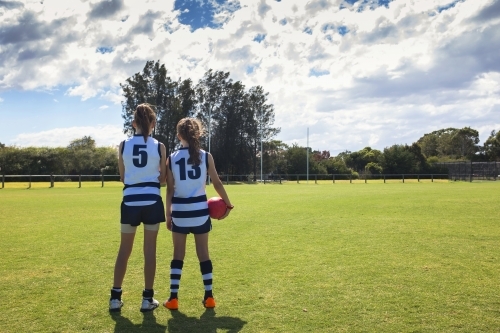 Two girl AFL players standing on the football ground