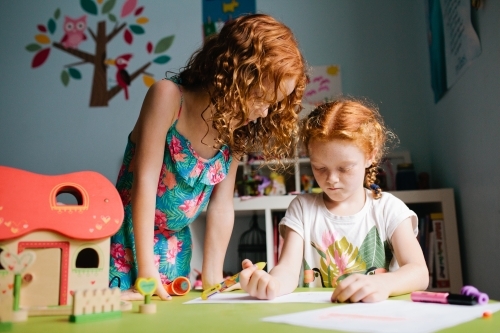 Two girls drawing at a table in a bedroom - Australian Stock Image