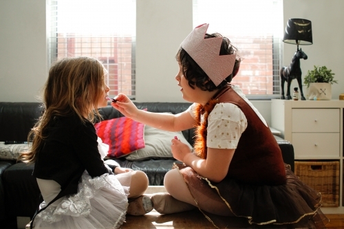 Two girls dressed as princesses playing putting on makeup - Australian Stock Image