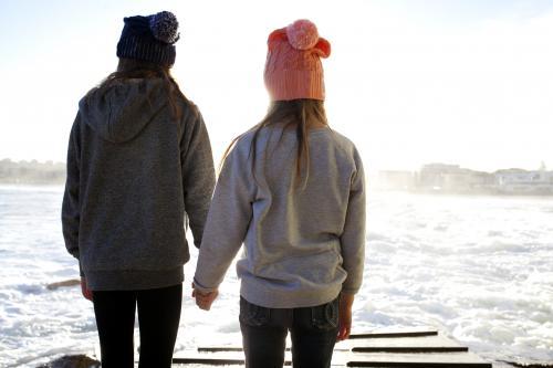 Two girls holding hands on a boat ramp in the afternoon light - Australian Stock Image