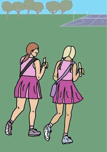 Two girls in pink sport uniforms walking across green grass to netball court eating bananas