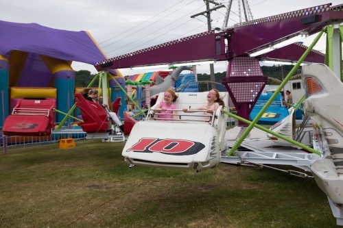 Two girls on an amusement ride at a country show - Australian Stock Image