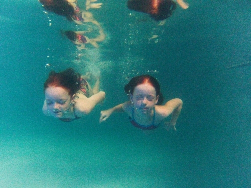 Two girls swimming underwater in a pool - Australian Stock Image