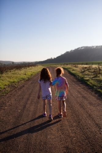 Two girls walking along a dirt road - Australian Stock Image