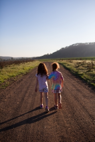 Two girls walking along a dirt road