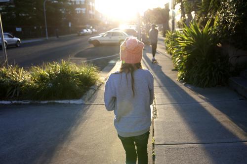 Two girls walking away on a footpath in the afternoon light - Australian Stock Image