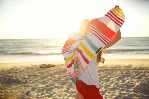 Two girls walking on the beach sharing a beach towel
