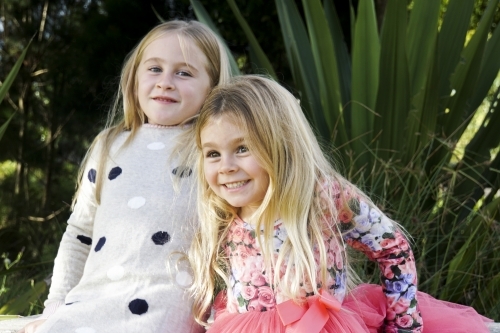 Two girls with blonde hairs playing outdoors - Australian Stock Image