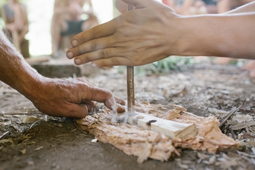 Two hands engaged in flint knapping to create fire. - Australian Stock Image