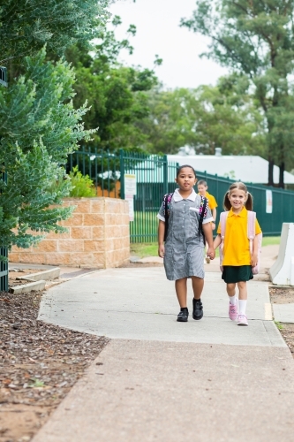 Two happy school friends walking to school together - Australian Stock Image
