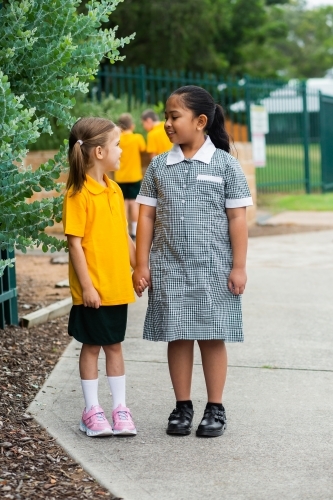 Two happy school friends walking to school together - Australian Stock Image