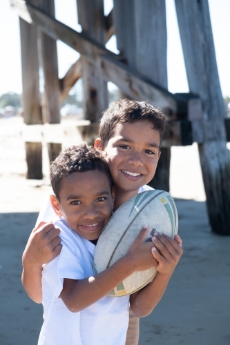Two indigenous boys playing under a wooden pier