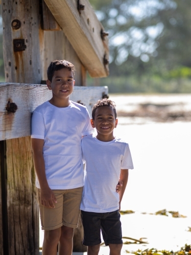 Two indigenous boys standing next to a timber house frame