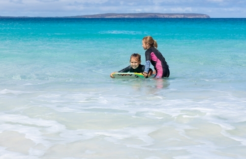 two kids in the water with a boogie board - Australian Stock Image