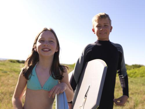 Two kids preparing to go body boarding - Australian Stock Image
