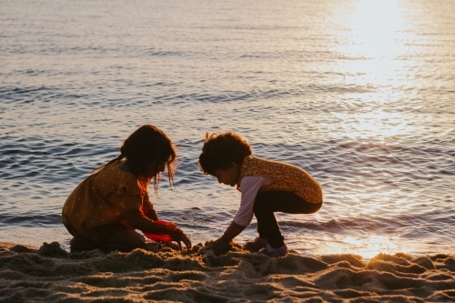 Two little girls building sand castles at the beach - Australian Stock Image