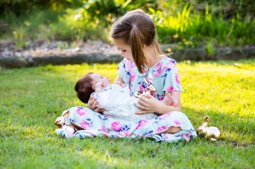 Two little girls cuddling outside with Easter rabbits - Australian Stock Image